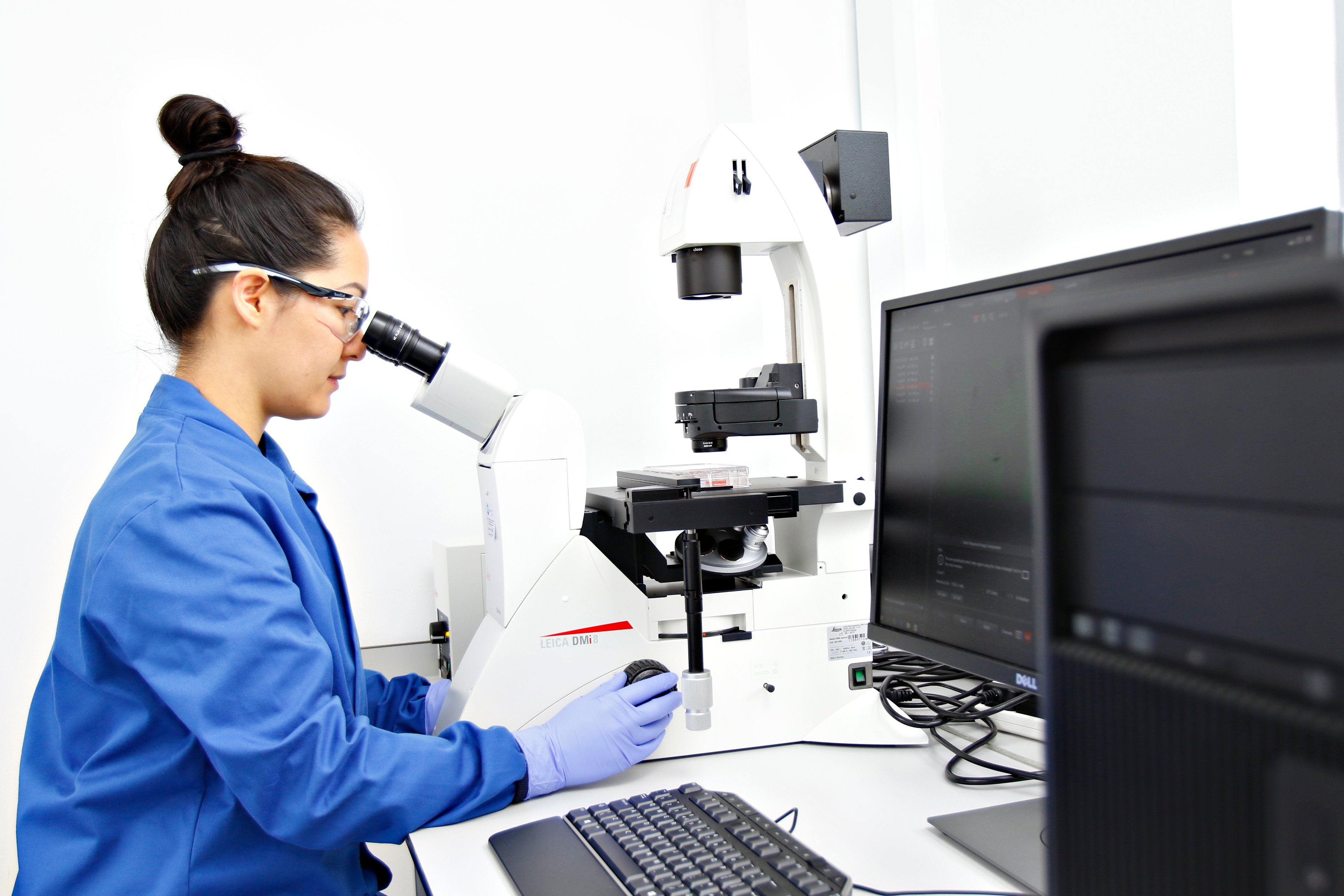 A REPROCELL stem cell scientist looking down a microscope