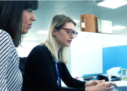 An image of two female presenting people looking at a computer 