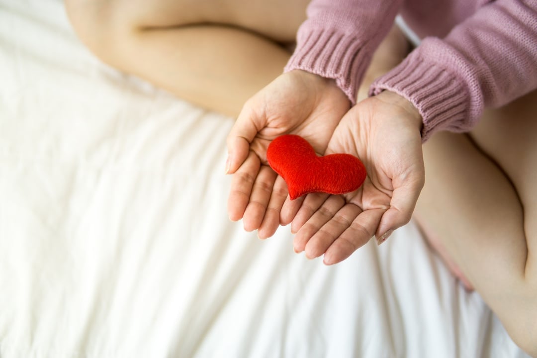 Woman with heart on palms - photo by Puwadon Sang-ngern