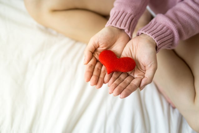 Woman with heart on palms - photo by Puwadon Sang-ngern