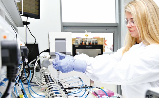 A woman with blonde hair reaches out to operate an Ussing Chamber system 